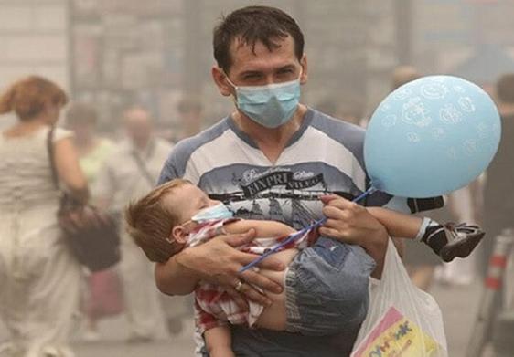 Un padre y su hijo se protegen de la contaminación urbana con mascarillas.