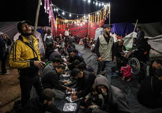 Palestinos degustan en Rafah la comida nocturna con la que se rompe el ayuno diario del Ramadán.