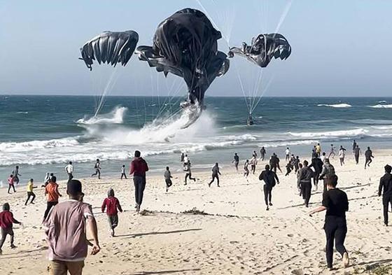 Paracaídas con ayuda humanitaria caen sobre una playa de Gaza.