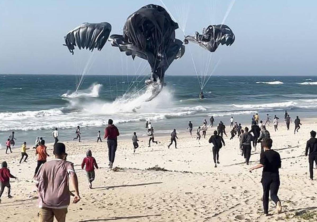 Paracaídas con ayuda humanitaria caen sobre una playa de Gaza.