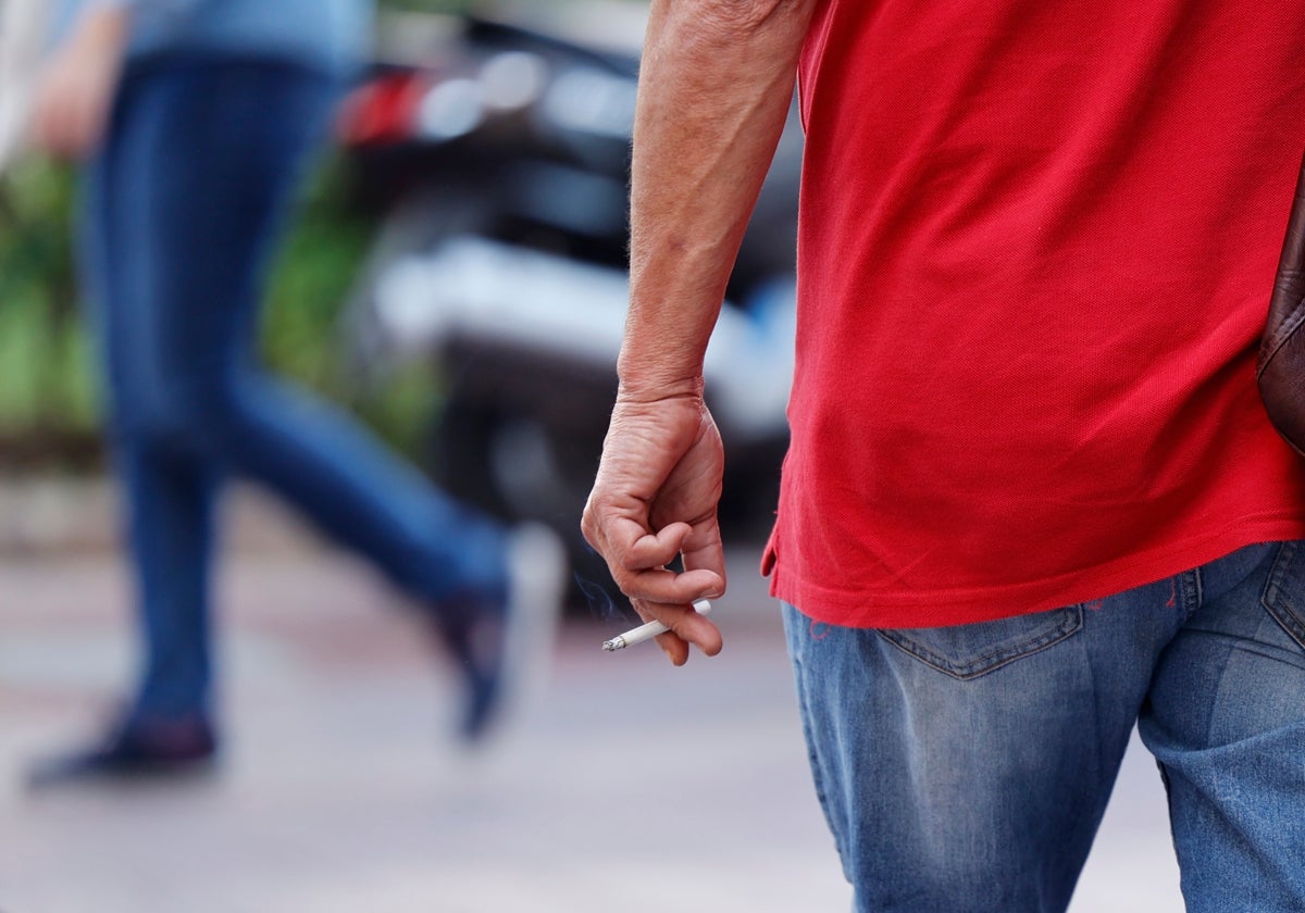 Un hombre fuma un cigarrillo mientras camina por la calle.