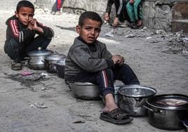 Niños palestinos esperan en una calle de Rafah a que les suministren algo de comida.