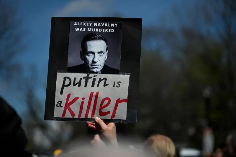Washington'da bir protestocu, başkanın zaferini öğrendikten sonra Navalni'yi anan bir pankart ve 'Putin bir katildir' efsanesini taşıyor.