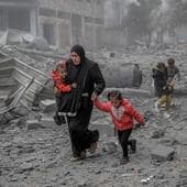 Una madre abandona con sus hijos un barrio de Gaza bombardeado por Israel.