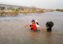Una familia de migrantes cruza el río Grande desde México a Texas.