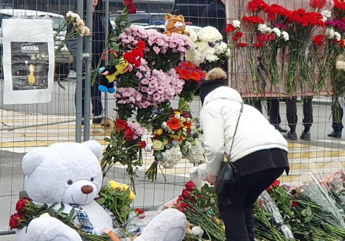 Una mujer deposita flores en los aledaños del Crocus City Hall.