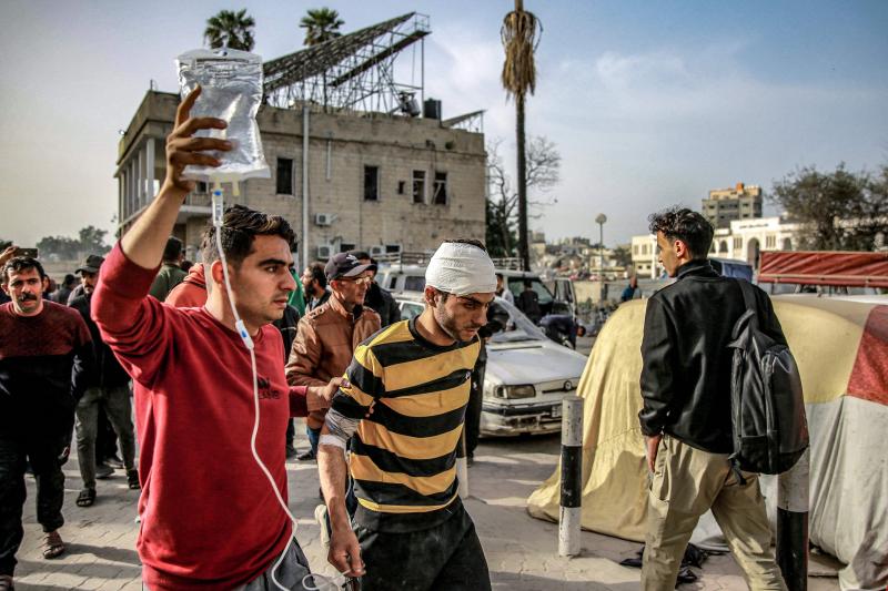 Un hombre ayuda a otro con el gotero en el exterior del hospital Ahli en Ciudad de Gaza.