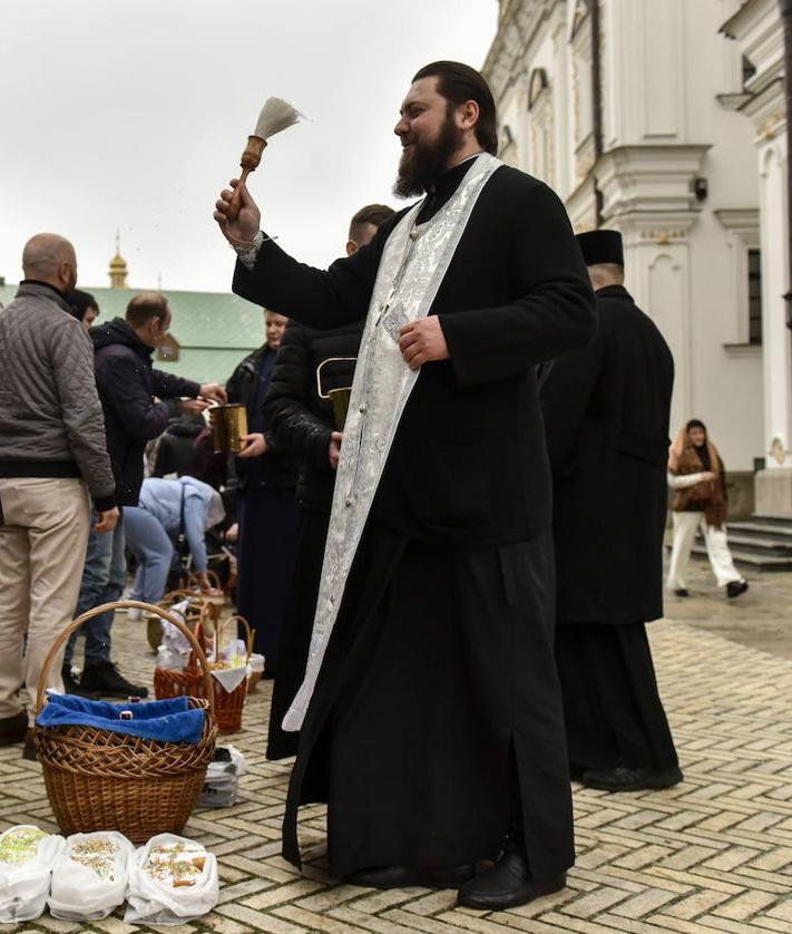 Imagen secundaria 2 - Ucranianos hacen cola con sus cestas a la espera de ser bendecidas mientras otros creyentes colocan velas en una iglesia de la capital. 