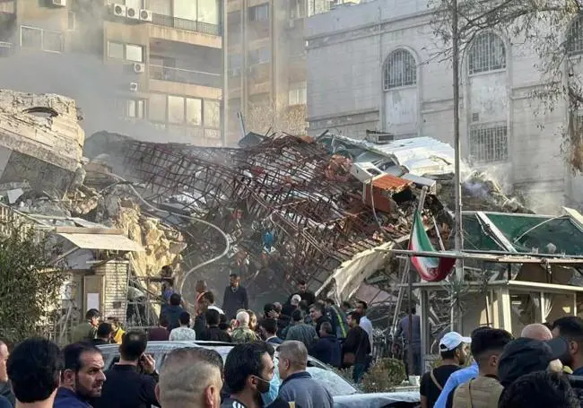 An Iranian flag flies next to the rubble of the diplomatic building in Damascus.
