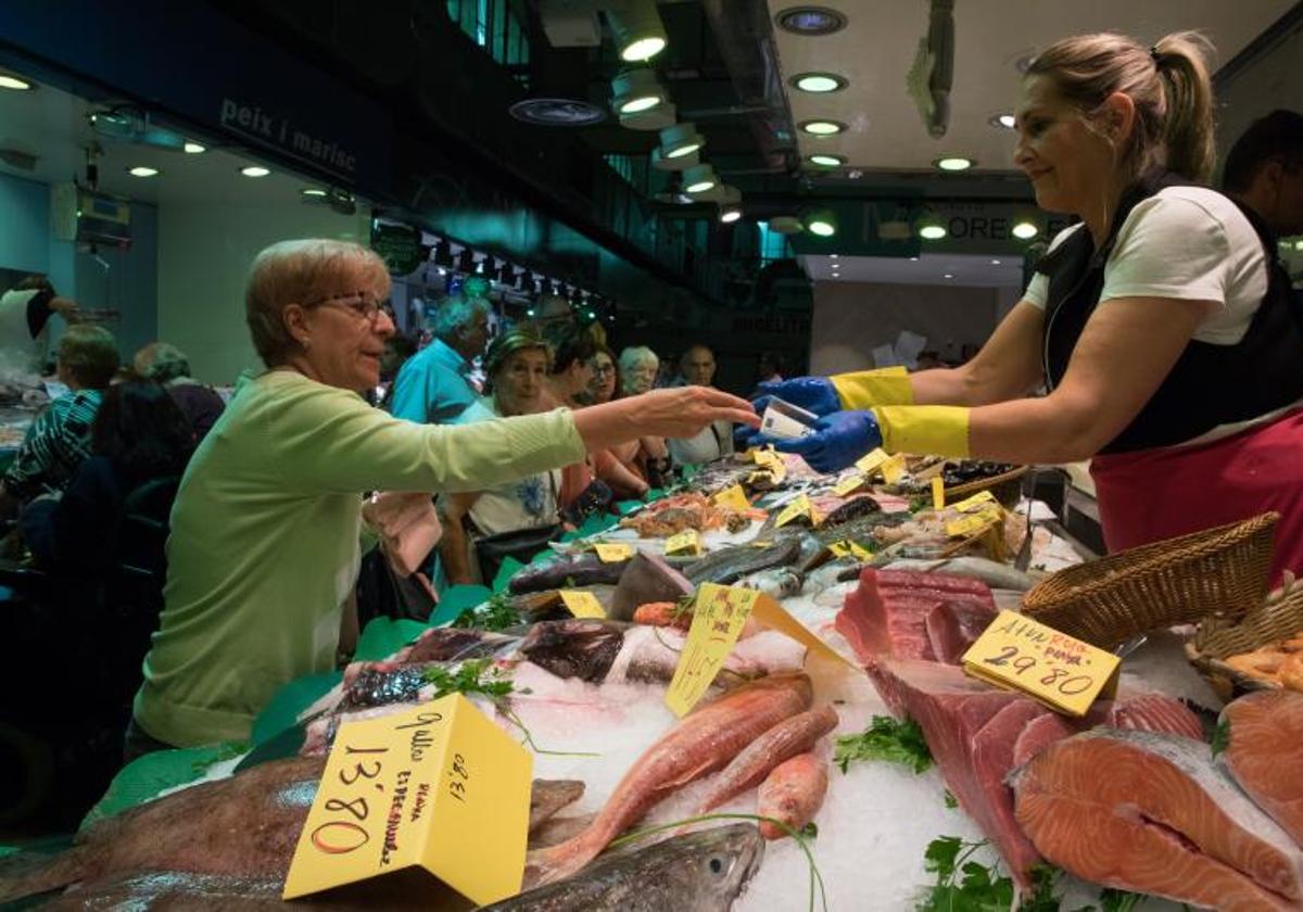 Una mujer hace la compra en la pescadería de un mercado.