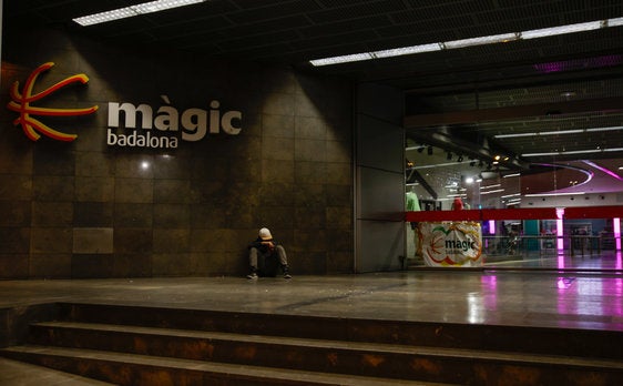 Una persona sentada en una entrada del centro comercial Màgic Badalona