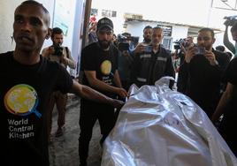 Miembros de World Central Kitchen transportan a la morgue de Rafah el cadáver de uno de los cooperantes muertos en el ataque.