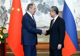 El ministro de Exteriores chino, Wang Yi, estrecha la mano a su homólogo ruso, este martes en Pekín.
