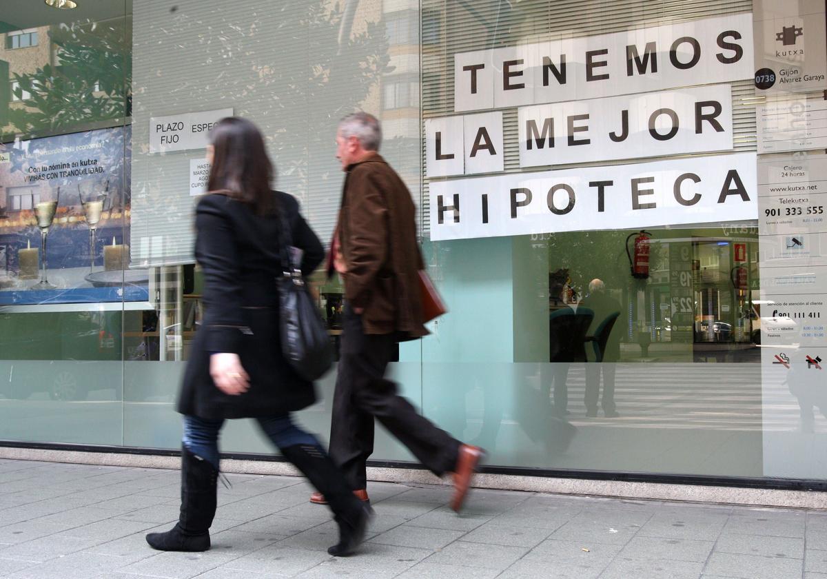 Dos personas pasan por delante de un cartel de promoción de un banco.