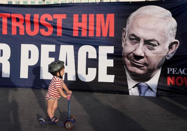 Un niño observa propaganda de un Netanyahu que apela a la paz.