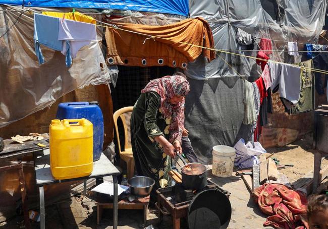 Una mujer cocina en un campo para desplazados palestinos en Rafah.