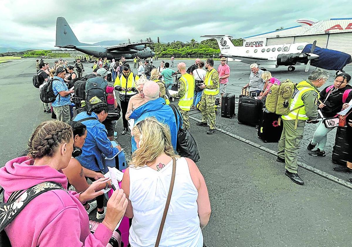 Turistas hacen cola en el aeropuerto de Magenta para ser evacuados en un avión militar neozelandés.