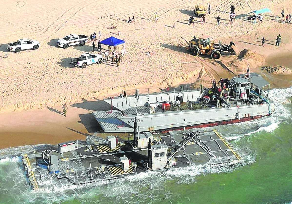 Parte de la estructura del muelle flotante y un buque, embarrancados en una playa israelí.