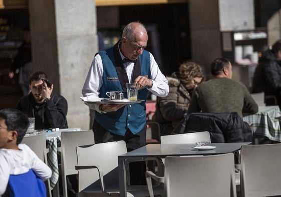 Un camarero atiende en la terraza de un bar.