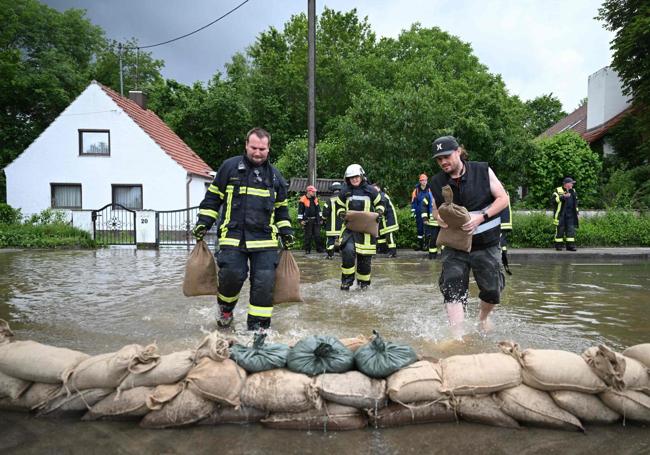 Los bomberos y un ayudante amontonan sacos de arena