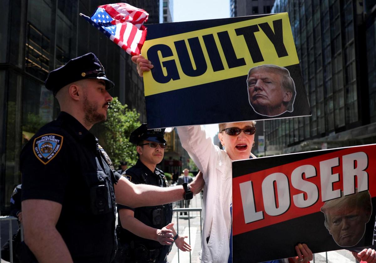 Un manifestante anti-Trump sostiene pancartas frente a la Torre Trump, en Nueva York.