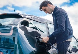 Un hombre recarga su coche eléctrico.