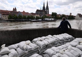 Un hombre observa el río Danubio a su paso por Regensburg junto a unos sacos de arena para contener la riada.