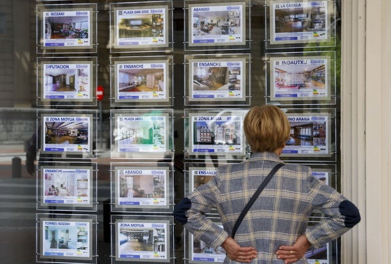 Una mujer mira la oferta de viviendas en una inmobiliaria en Bilbao