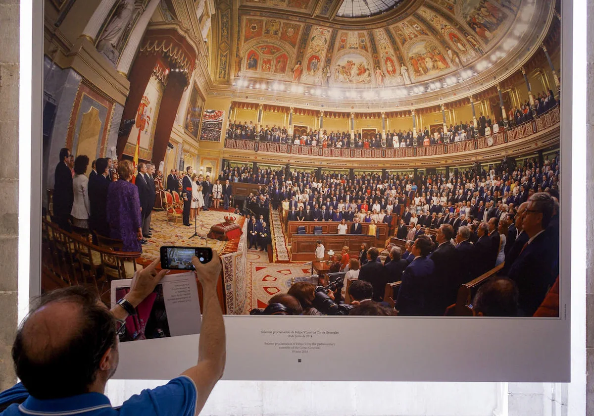 Un visitante fotografía la imagen de la ceremonia de coronación de Felipe VI en el Congreso.