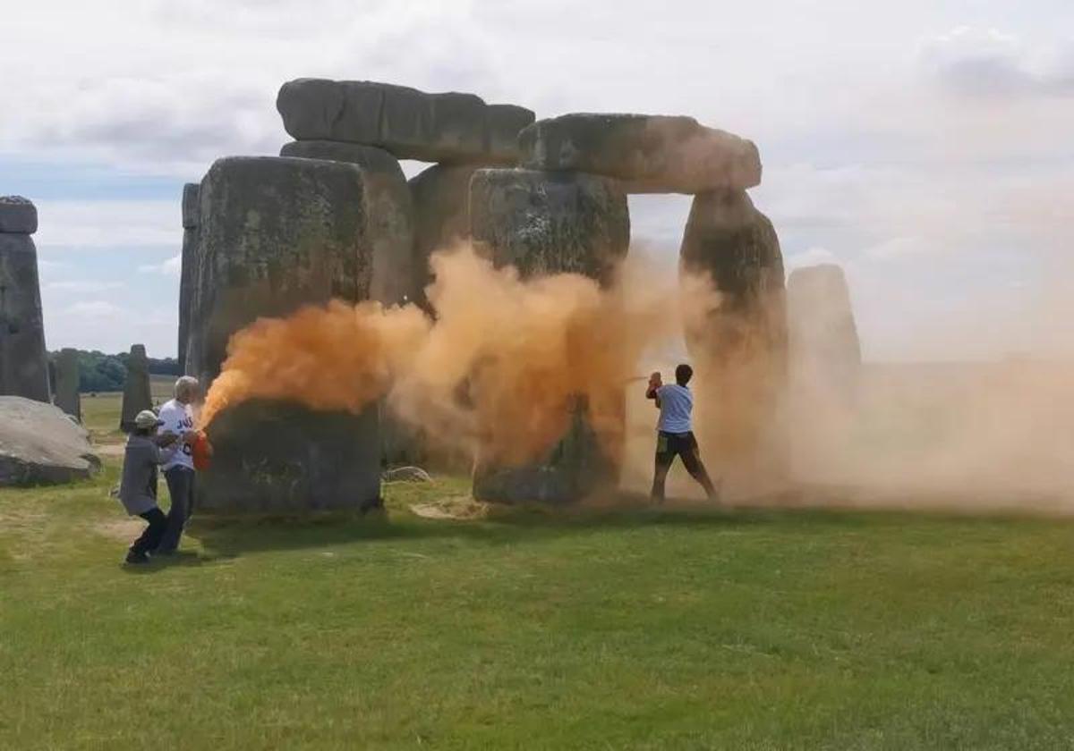 Los dos activistas rocían el monumento con spray naranja.