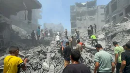 Un grupo de palestinos busca supervivientes bajo un edificio reducido a escombros por las bombas.