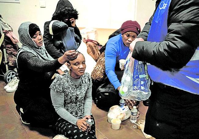 Voluntarios distribuyen bolsas de alimentos a mujeres en Saint-Denis.