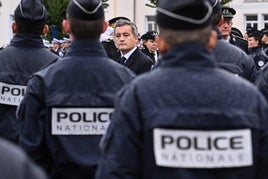 El ministro del Interior francés, Gerald Darmanin, flanqueado por policías en un acto.