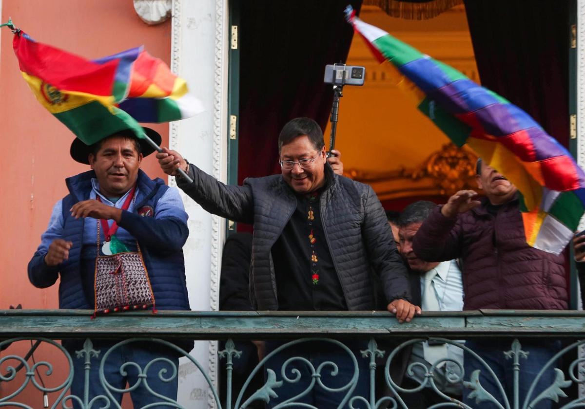 Arce agita una bandera boliviana acompañado por su gabinete en un balcón del palacio presidencial.