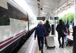 Pasajeros con sus maletas por una estación de tren.