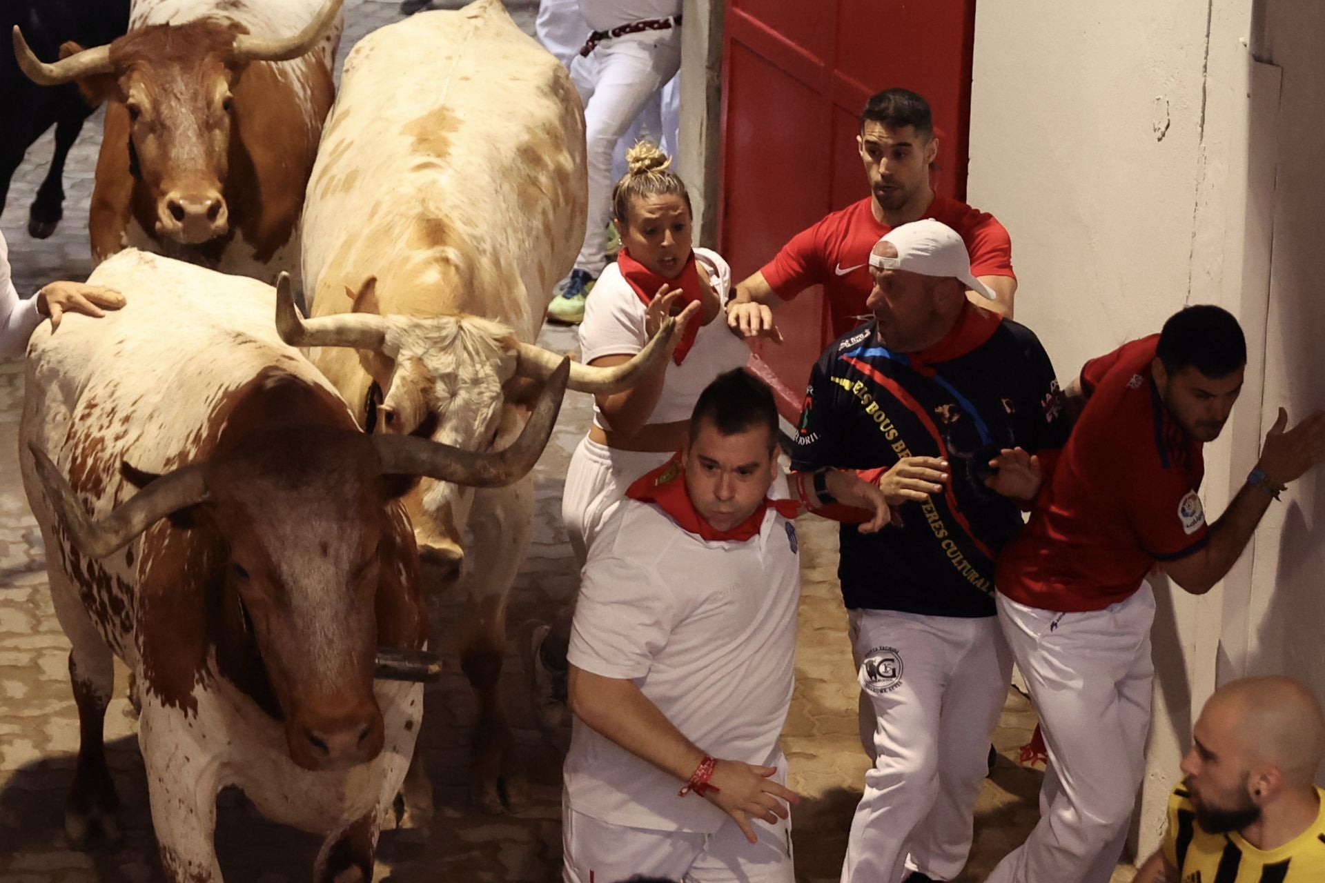 Mozos caen mientras son perseguidos por toros de Victoriano del Río en el tercer encierro de los Sanfermines este martes.