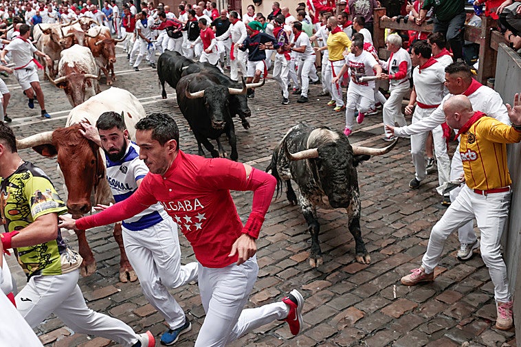 Mozos son perseguidos por toros de Victoriano del Río en el tercer encierro de San Fermín.