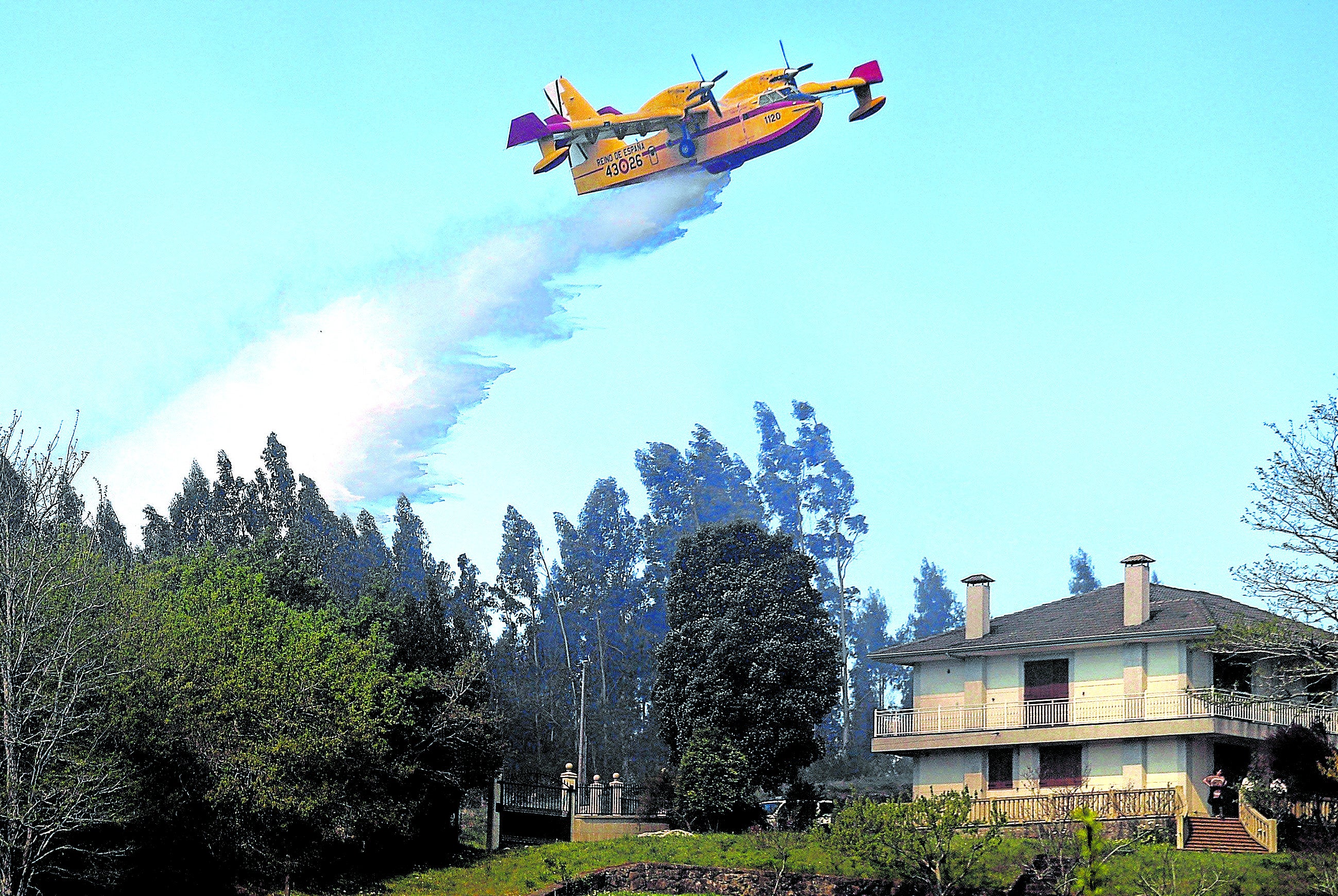 Imagen principal - De arriba a abajo, un 'botijo' del '43' descarga sobre un incendio cercano a una vivienda los 6.000 litros de agua que lleva en sus tanques. Dos pilotos en la cabina de un avión CL-415, más moderno que sus 'hermanos', los Canadair 215, ambos modelos del '43'. Y la calavera con el casco, símbolo oficioso de los 'Corsarios'.