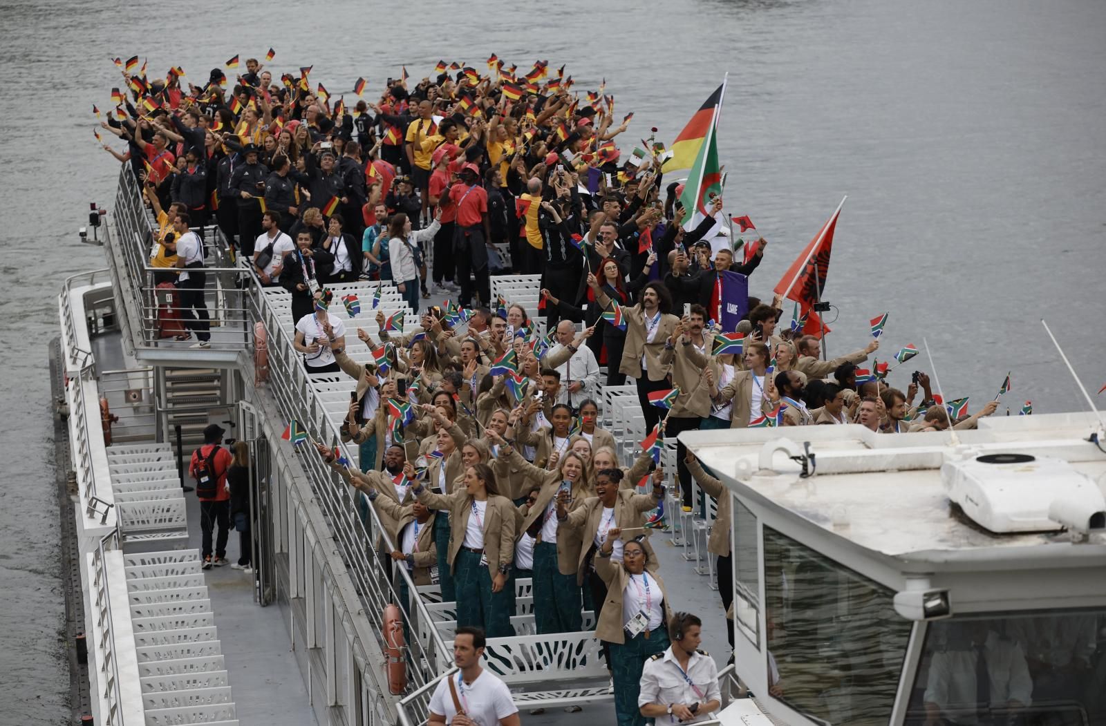 Atletas de Alemania, Sudáfrica y Montenegro a bordo de un barco en el desfile flotante sobre el río Sena.