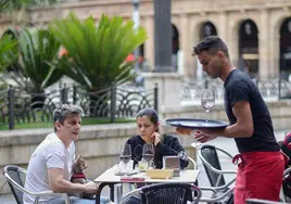 Clientes en una terraza de un bar atendidos por un camarero.