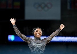 Simone Biles, sonriendo después de ejecutar el ejercicio de barras en París 2024.