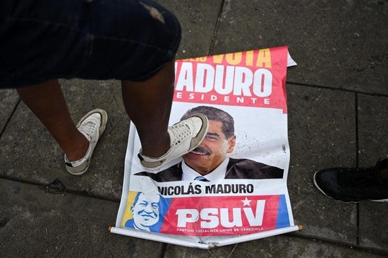 Una mujer pisotea un cartel electoral con el rostro de Maduro en Caracas.