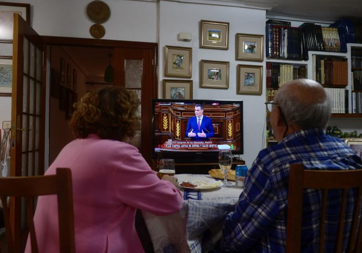 Dos personas mayores viendo la televisión en su casa