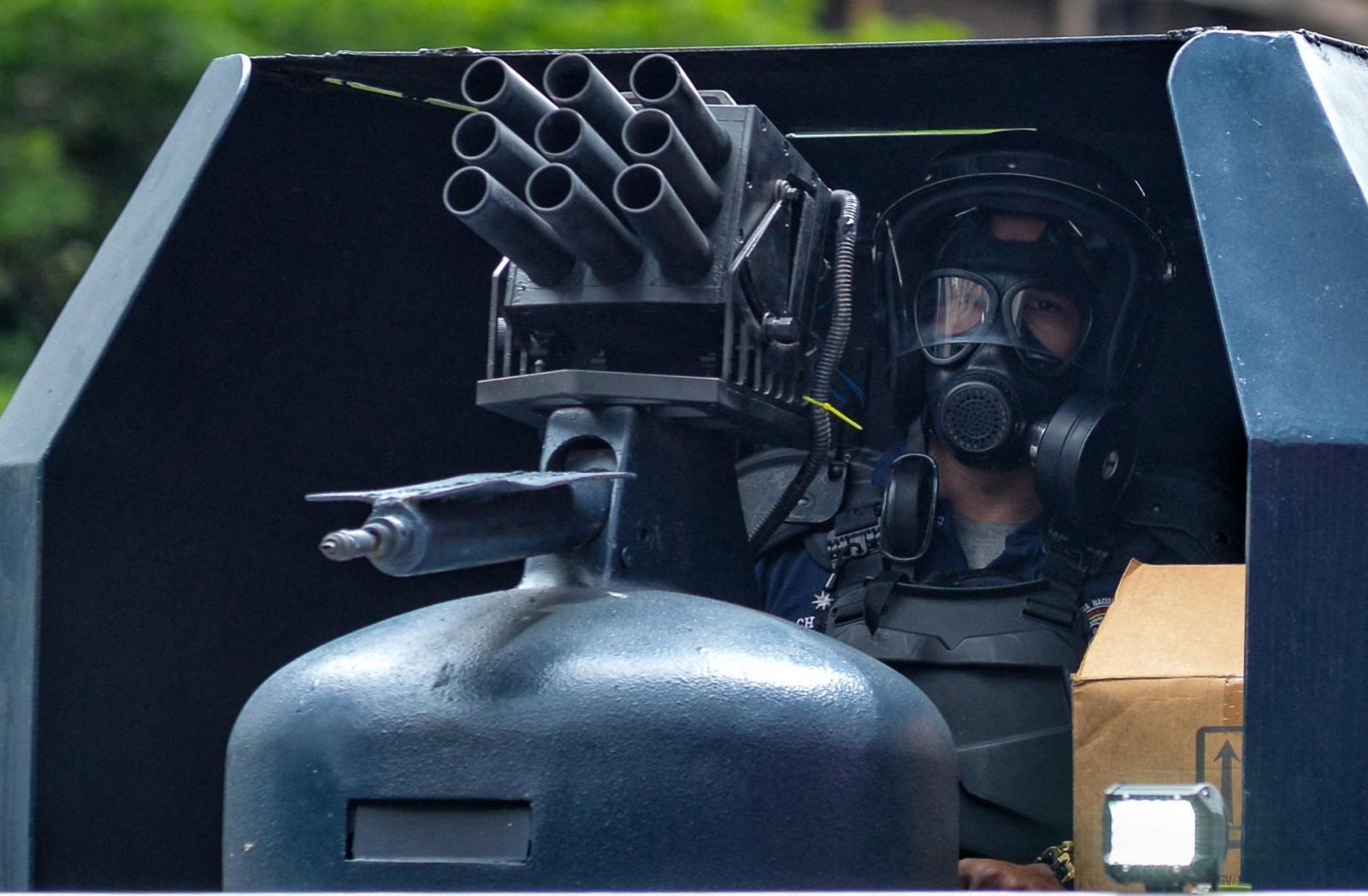 Un miembro de la Policía Nacional hace guardia en una calle de la capital, provisto de gas lacrimógeno y un aparato para disparar balas de goma.