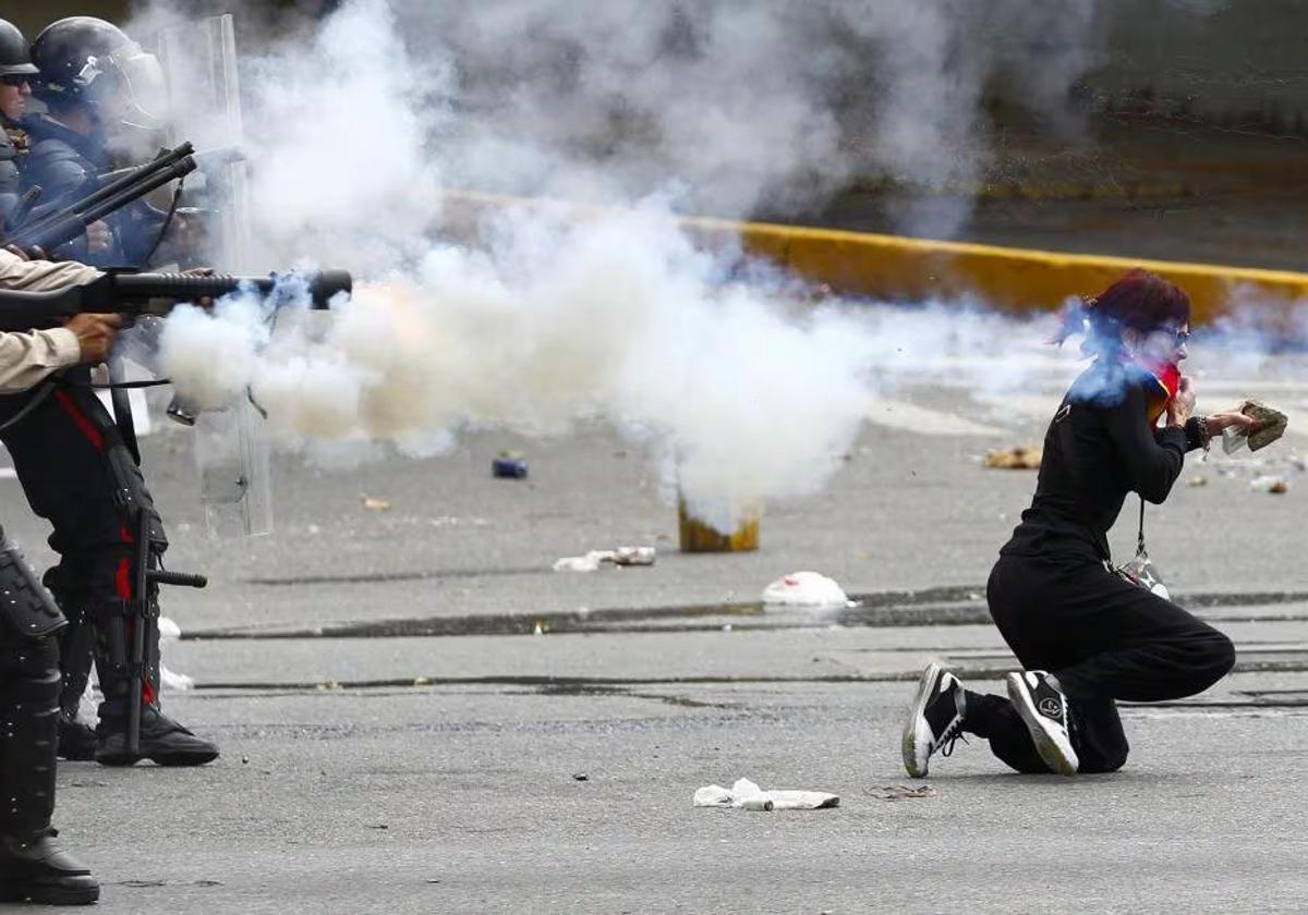 Una joven huye de los gases lacrimógenos.