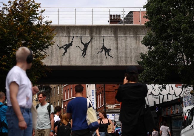 Monos colgante de un pasarela de la estación de metro de Shoreditch High Street.