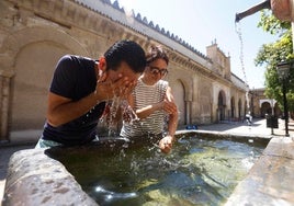 Unos turistas se refrescan por el calor asfixiante en una fuente de la Mezquita de Córdoba.