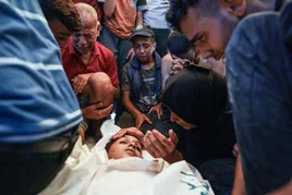 Familiares junto a un niño muerto en un hospital de Gaza.