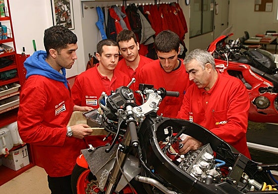 Un grupo de alumnos que estudian una FP para mecánico atienden las explicaciones del experto.