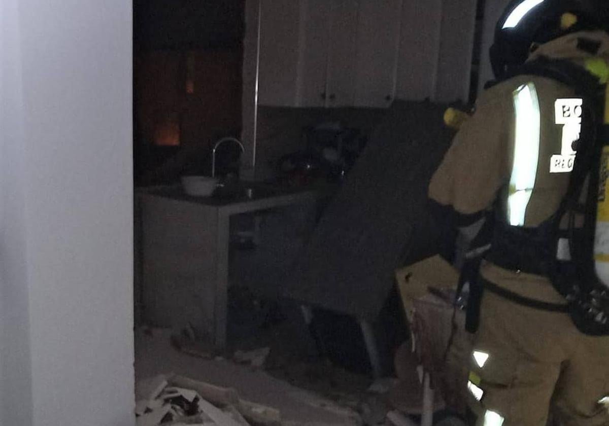 Un bombero trabaja en el interior de la vivienda donde estalló la bombona de butano.